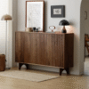Premium fluted wooden shoe sideboard by WoodBee Craft featuring a 3-door dark walnut frame, vertical fluted paneling, and unique arched legs in a minimalist room.